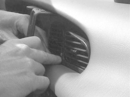 En hand monterar en bygel på en bils luftutlopp.