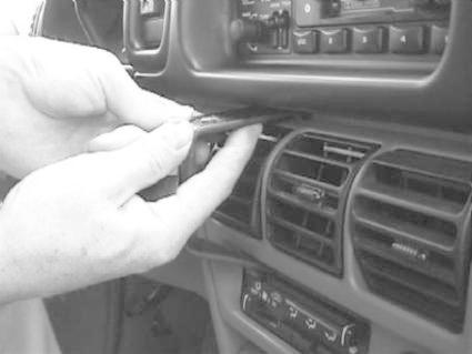 En hand justerar ett luftventilationsgaller i en bilpanel.