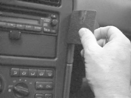 En hand håller i en svart monteringsbygel i en bilinteriör.