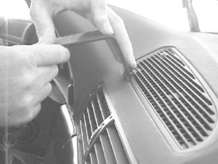 En person använder ett verktyg för att arbeta med instrumentpanelen i en BMW E38.