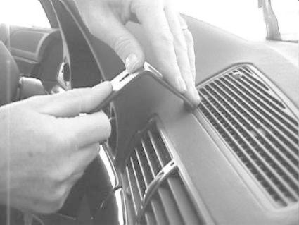 En hand justerar en panel på instrumentbrädan i en BMW E38.