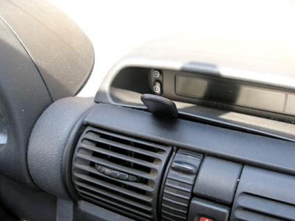 En del av instrumentbrädan med luftutlopp och en knapp.