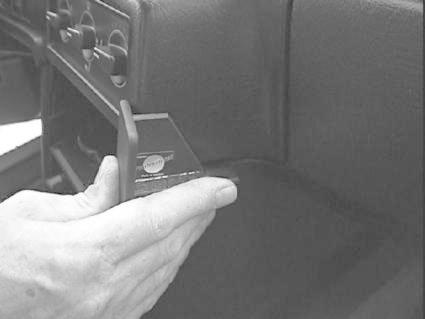 En hand håller en vinklad del som verkar vara en del av inredningen till Volvo 740/940.