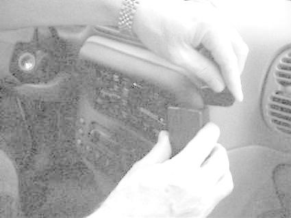 En hand justerar en komponent på en bilinteriör.