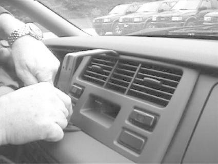 En person justerar bilens mittkonsol med luftventiler och knappar.