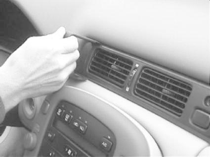Hand som installerar en monteringsbygel vid luftventilen i en bil.
