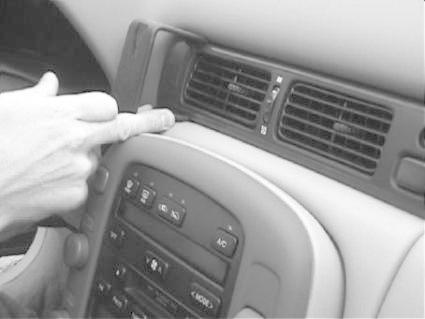 En hand pekar på ventilationen i en bilinteriör.