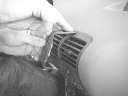 En hand installerar en monteringsbygel vid luftutloppet i en bil.