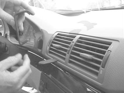 En hand fixar luftventiler i en BMW E39-interiör.
