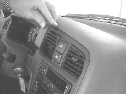 En hand pekar på instrumentpanelens kontrollknappar i en Nissan Primera.