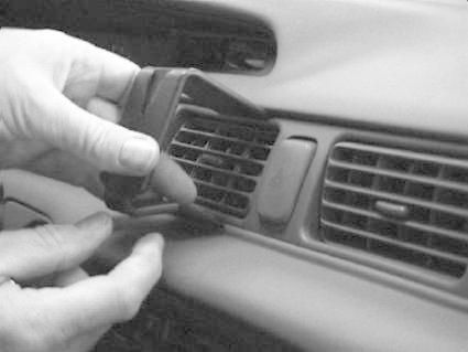 En hand håller en del som monteras i bilens luftventil.