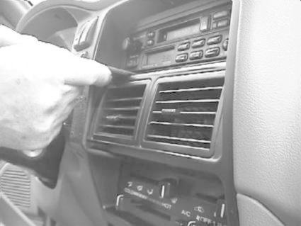 En hand pekar på luftventiler i en bil interiör.