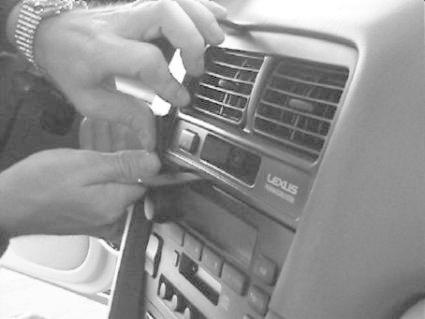 En person installerar en del i mittkonsolen av en Lexus ES.