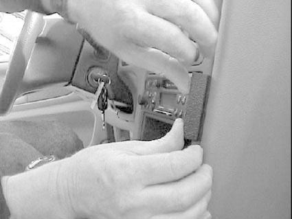 Två händer justerar någon del av fordonets interiör, troligen stereon.