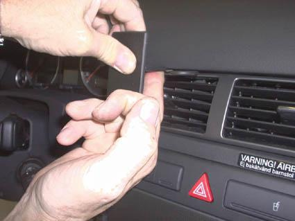 En person installerar en komponent i instrumentbrädan på en Audi A6.