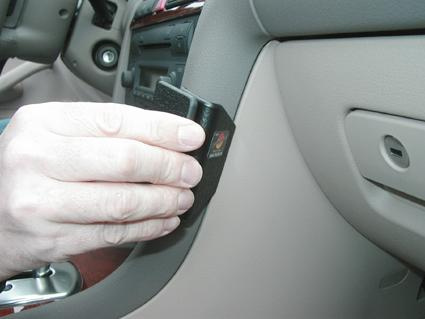 En hand håller en vinklad del i en bilinteriör.