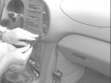 En hand arbetar med bilens mittkonsol och stereoutrustning.