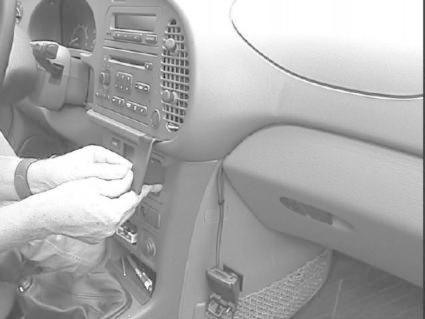 En person installerar en del i bilens mittkonsol.