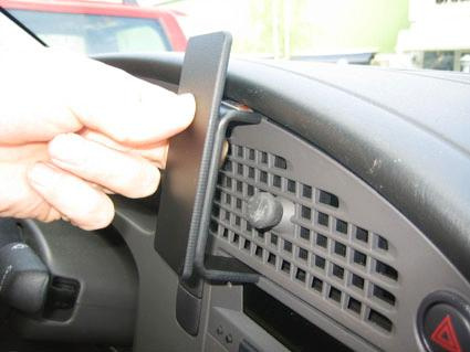 En hand håller i en svart del som fästs på en instrumentbräda i en bil.