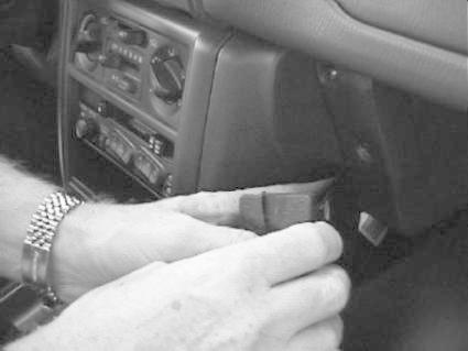 En hand ansluter en komponent i en bils instrumentpanel.