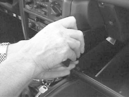 En hand som justerar en kontroll eller en del i ett bilinteriör.