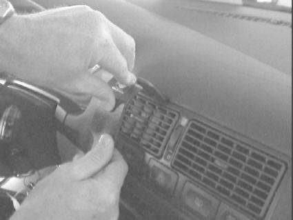 Händer installerar en del i instrumentpanelen på en Volkswagen Golf IV.