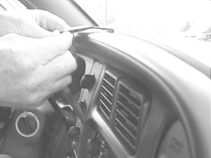 En hand installerar en detalj på instrumentbrädan i en Dodge Ram.