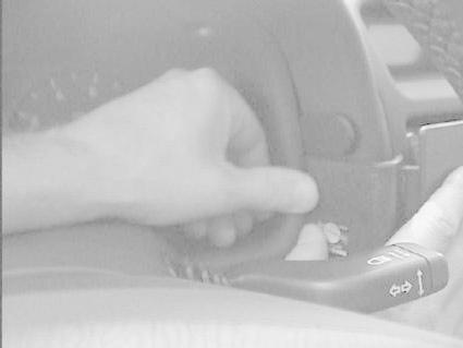 En hand greppar ratten med en knapp för blinkers i fokus.