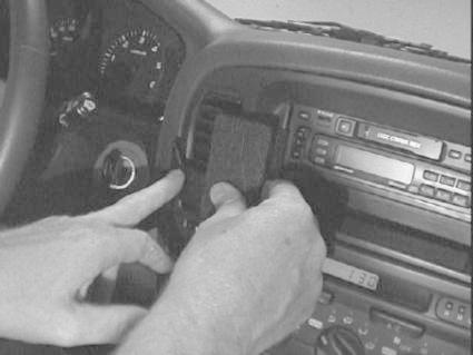 Händer installerar en dubbeldin-radiopanel i en Toyota LandCruiser 100.