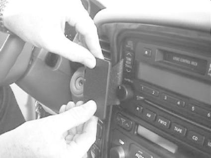 En person fäster en del på bilens instrumentpanel.