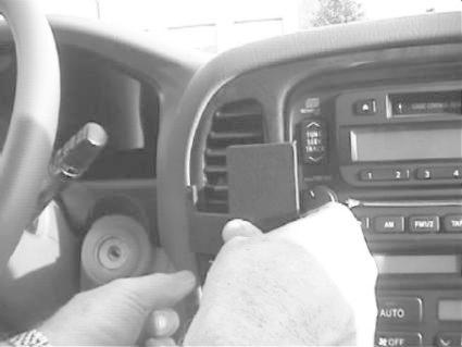 En person justerar eller installerar en enhet i bilens mittkonsol.