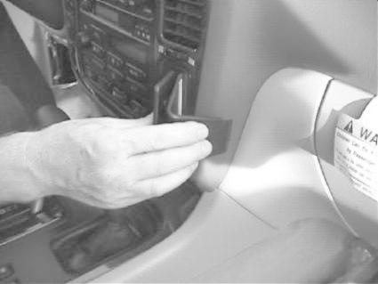 En hand fäster något på instrumentbrädan i en bil.