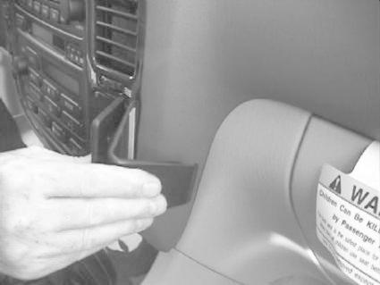 En hand som fäster eller justerar en del på en bilinteriör.