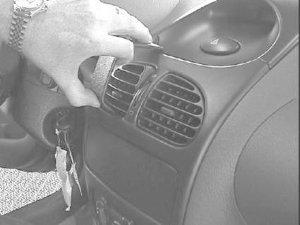 En hand justerar luftventilen i en Peugeot 206-interiör.