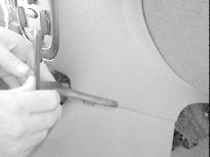 Montering av del i bil, fokus på verktyg och interiör.