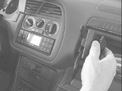 En hand justerar en del av bilens interiör, troligen stereo eller förvaringsutrymme.