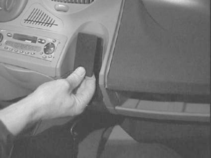 Hand som håller i en del av bilens interiör, troligtvis en knapp eller en enhet.