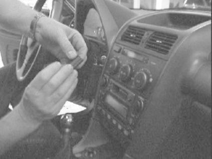 En person installerar något i bilens mittkonsol, troligen stereo eller tillbehör.