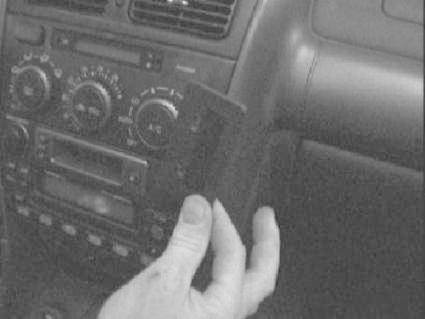 Bild på bilinteriör med hand som håller en enhet nära radion.