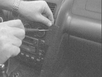 En hand arbetar med en verktyg på bilens instrumentpanel.