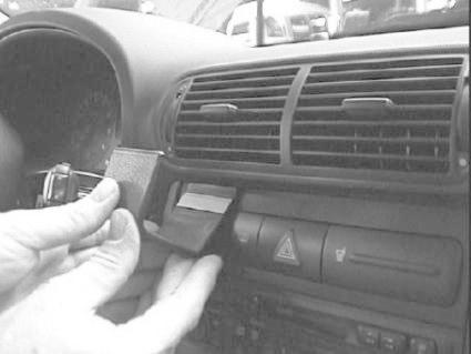 En hand installerar en del i instrumentpanelen på en bil.