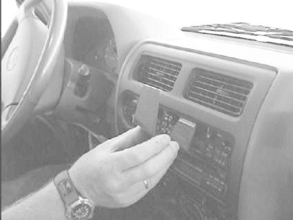 En hand som monterar något på bilens instrumentpanel.