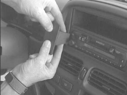 Ett par händer installerar en komponent i en bilradio.