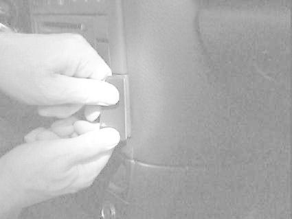 Händer som håller i en bilens komponent, troligen ett reglage eller en knapp.