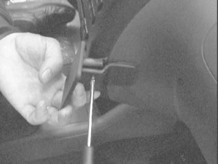 En hand som håller en monteringsbygel vid bilens inredning.