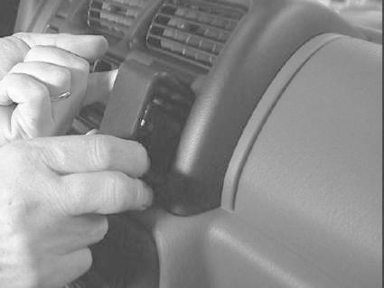 En hand fäster en monteringsbygel på inredningen av en Suzuki Jimny.