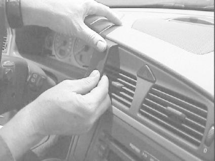 En person fäster en del på instrumentbrädan i en Volvo V70.