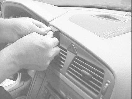 En person installerar något på instrumentpanelen i en Volvo V70.