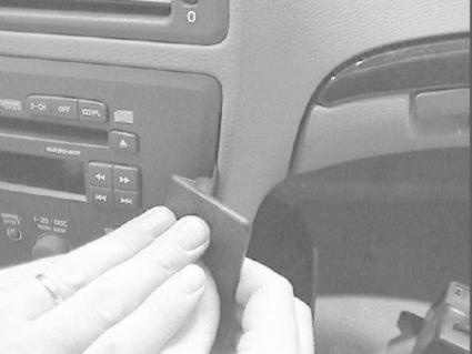 En hand håller en vinklad del vid en bilstereo i Volvo V70.