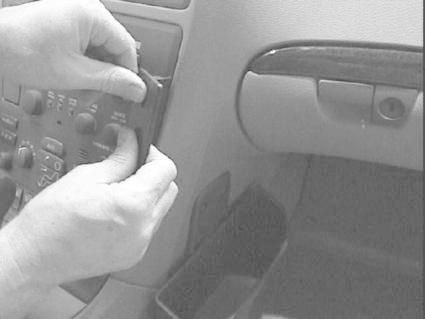 En person installerar eller justerar en del i bilens mittpanel.